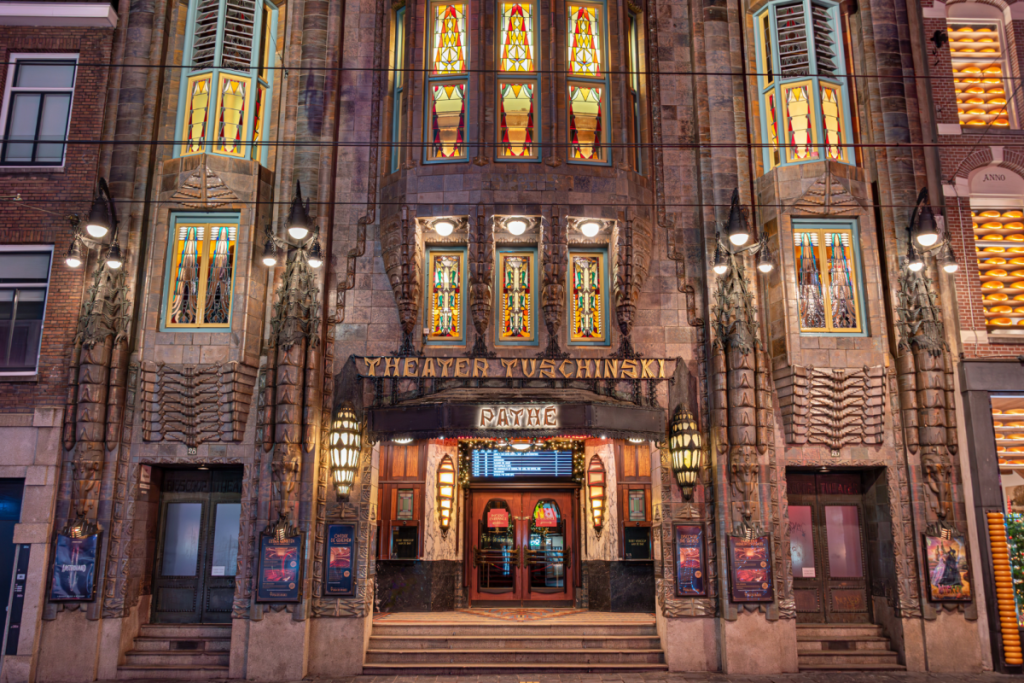 Die Fassade des Königlichen Theaters Tuschinski im Stil der Amsterdamer Schule mit beleuchteten Fenstern und klassischem Mauerwerk.