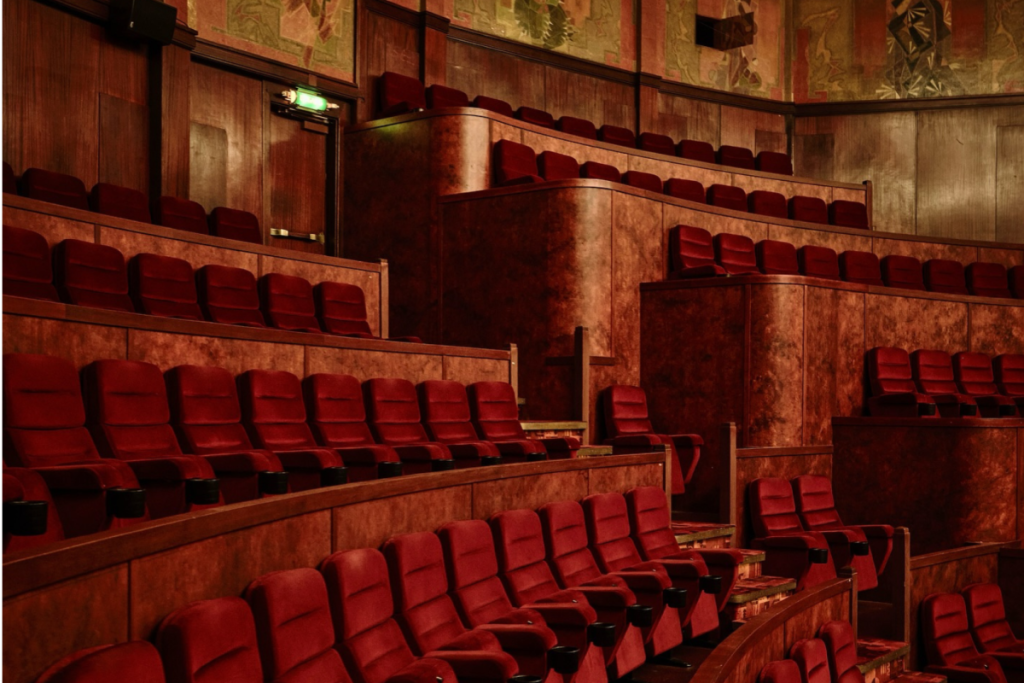 Stimmungsvoller klassischer Kinosaal im Königlichen Theater Tuschinski mit roten Plüschsesseln und warmer Holzvertäfelung.