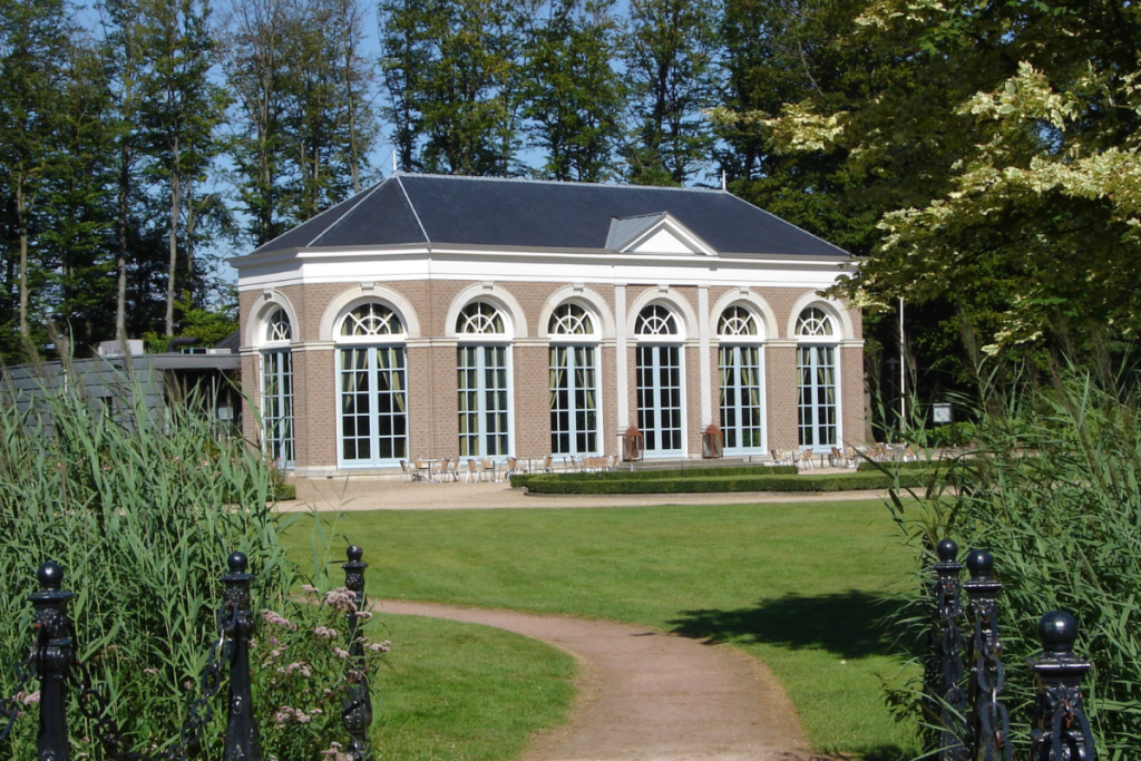 Die Orangerie Ruurlo mit großen Bogenfenstern und einer Terrasse im Schlossgarten.