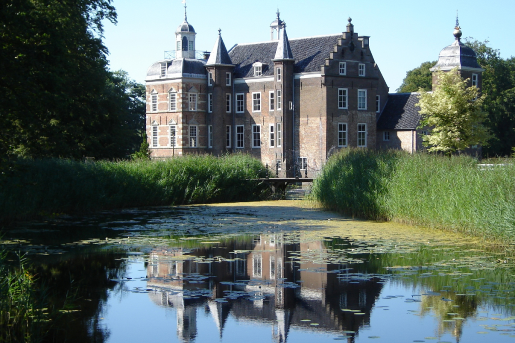 Außenansicht des historischen Schlosses Ruurlo mit Spiegelung im Kanalwasser.