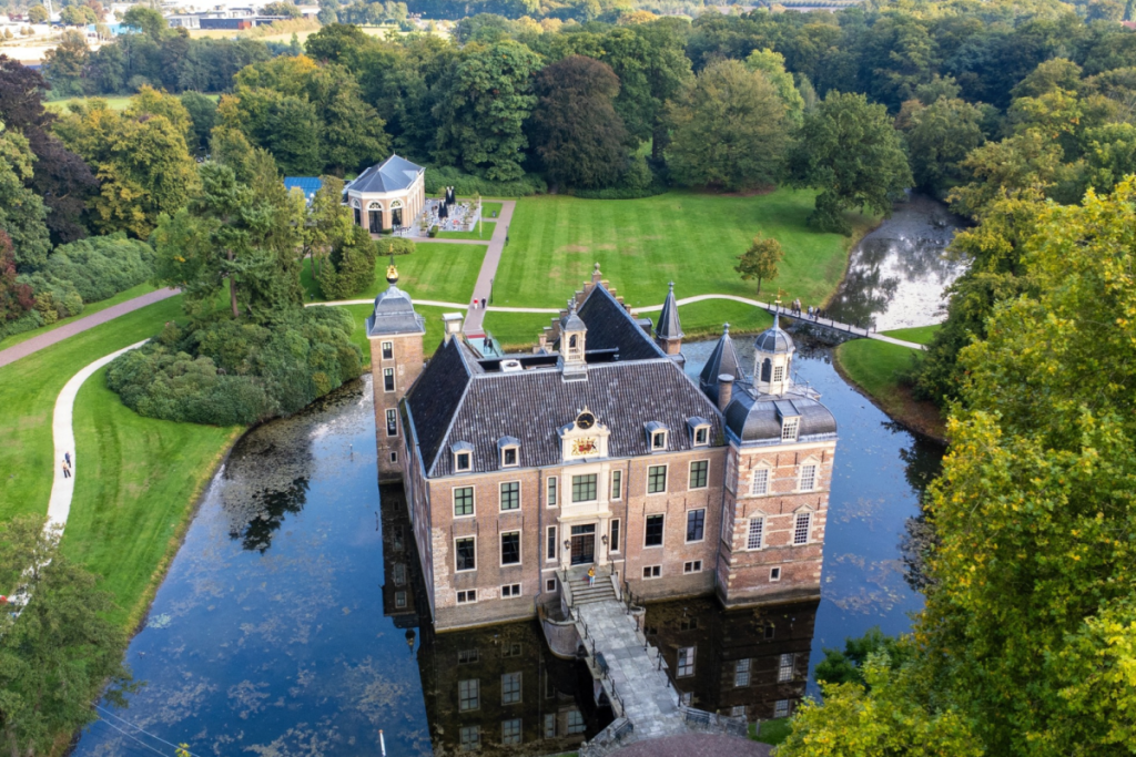 Luftaufnahme von Schloss Ruurlo mit dem umgebenden Wassergraben, der Zugbrücke und dem grünen Wald des Anwesens.