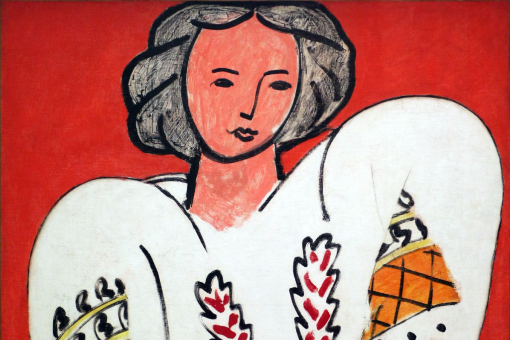 Das berühmte Gemälde „La Blouse Roumaine“ von Henri Matisse aus dem Jahr 1940 mit einer Frau in einer weißen, bestickten Bluse vor rotem Hintergrund.