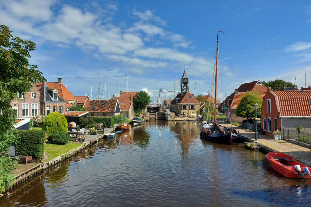 Blick auf den Stadtgraben von Hindeloopen mit dem denkmalgeschützten Kirchturm, den Holzbrücken und den traditionellen Schiffen