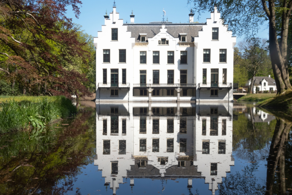 Fassade des märchenhaften Schlosses Staverden mit haarscharfer Spiegelung im Kanalwasser.