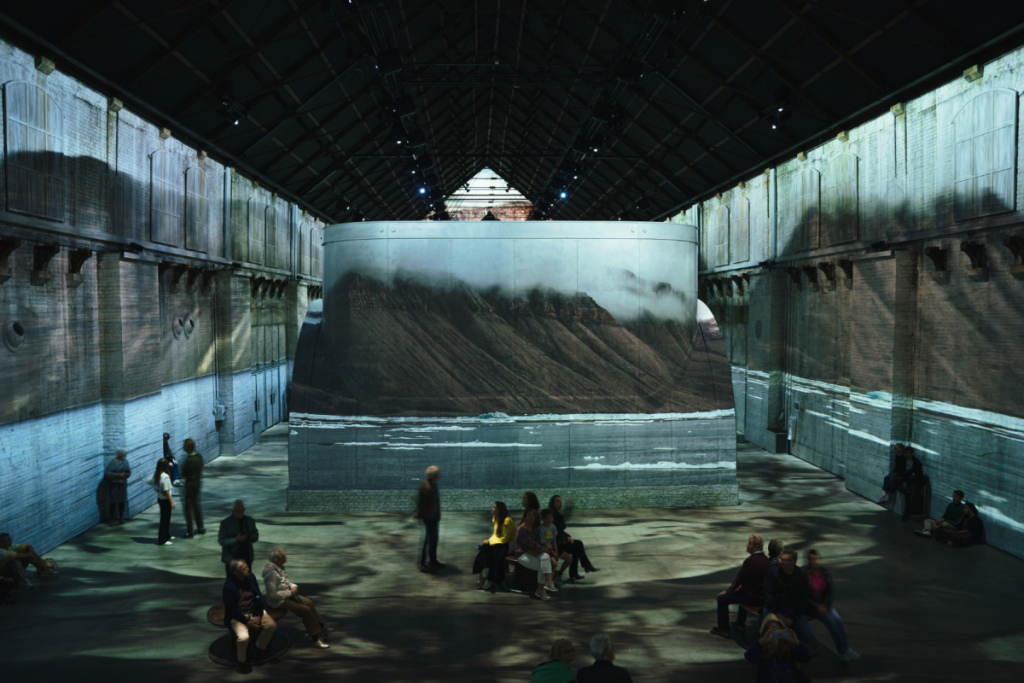 Les visiteurs découvrent la projection numérique captivante d’un paysage montagneux dans la grande salle de la Fabrique des Lumières.