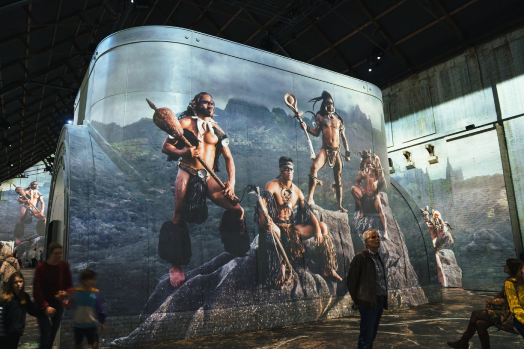 Les visiteurs de la Fabrique des Lumières découvrent une projection grandeur nature d’hommes autochtones en tenue traditionnelle, tirée d’une photo de Jimmy Nelson.