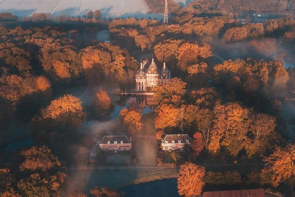 Luftaufnahme von Schloss Duivenvoorde und dem umliegenden Anwesen in warmen Herbstfarben.
