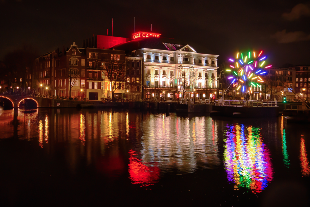 Farbenfroh beleuchtete Baumskulptur auf dem Wasser beim Königlichen Theater Carré an der Amstel.