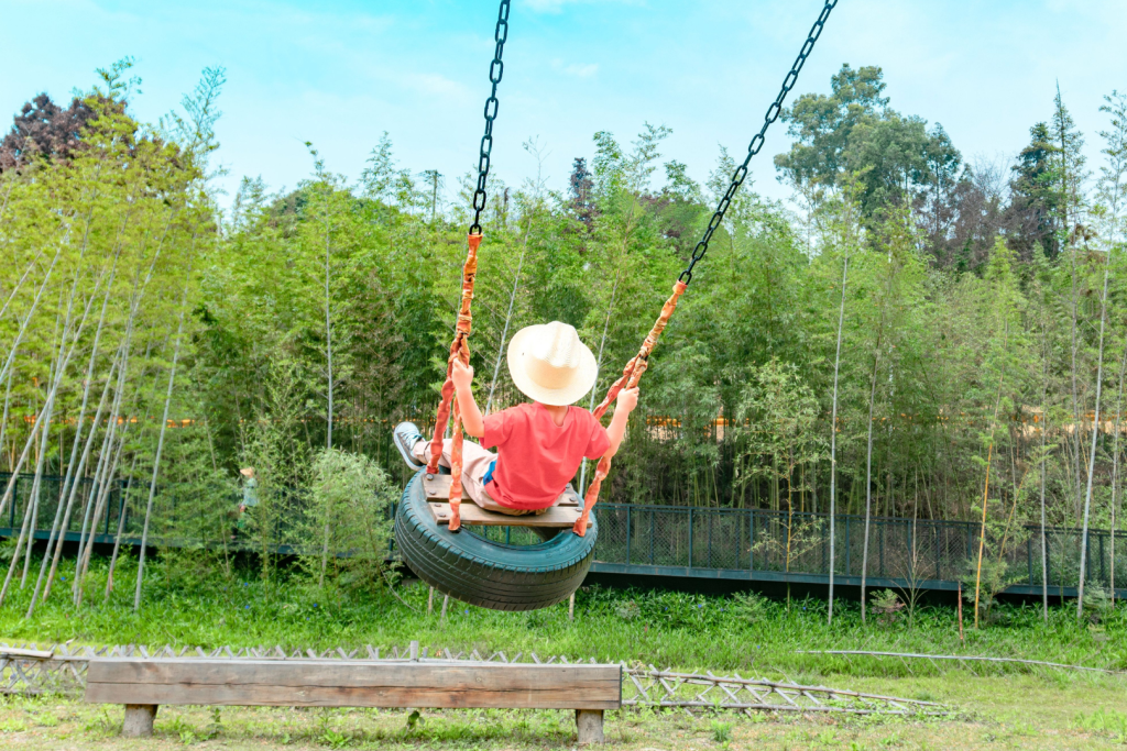 Kind auf einer Schaukel aus einem Autoreifen in einem grünen Park