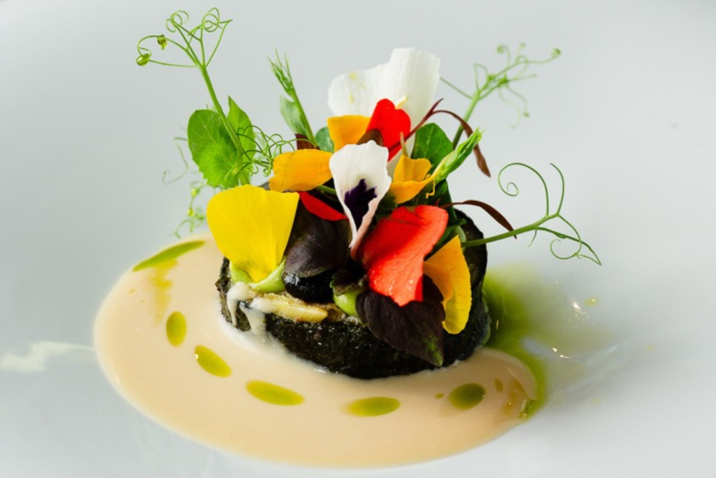 Raffiniertes Gericht von Chefkoch Alexander Ioannou mit geräuchertem Knollensellerie, Feldblumen und Hollandaise-Sauce im Restaurant Sinne.
