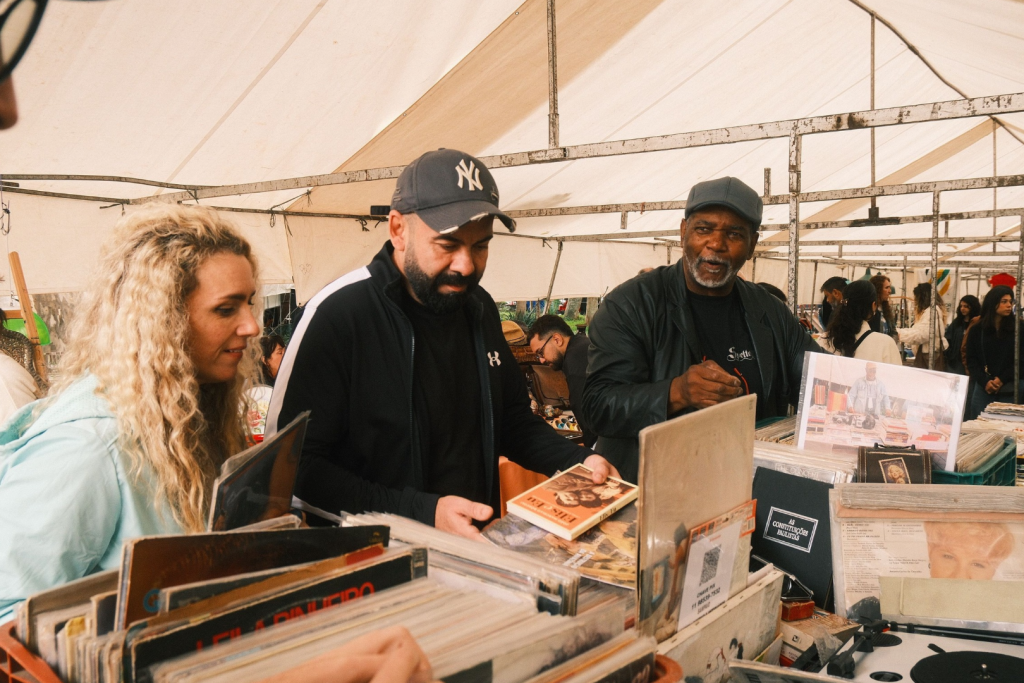 Besucher stöbern in Kisten voller Schallplatten an einem Plattenstand auf einem überdachten Markt.
