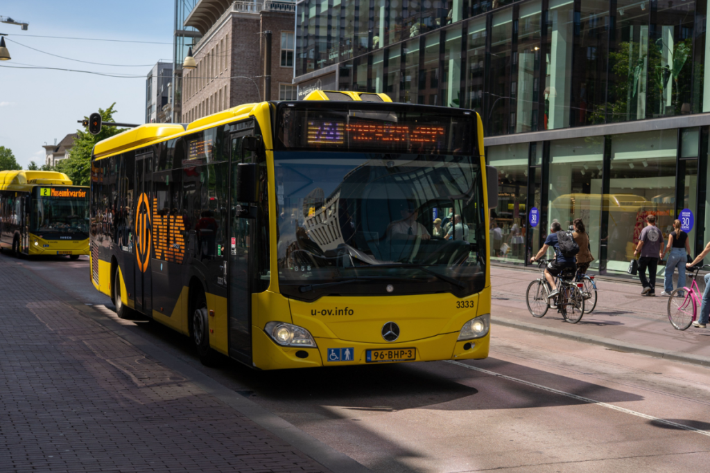 Ein gelber Regionalbus von U-OV fährt durch eine belebte Einkaufsstraße in der Stadt.