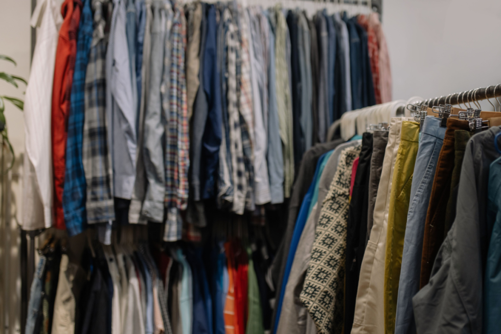 Kleiderständer voller sortierter Secondhand-Hemdchen, Jacken und Hosen während eines Kleidertauschs