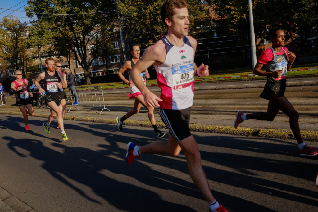 Die Läufer des TCS Amsterdam-Marathons laufen auf der asphaltierten Strecke entlang der Absperrungen in der Stadt.