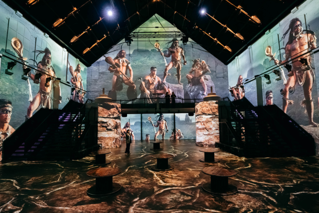 Lebensgroße 360-Grad-Projektionen von indigenen Kriegern in einer Berglandschaft von Jimmy Nelson an den Wänden der Fabrique des Lumières.