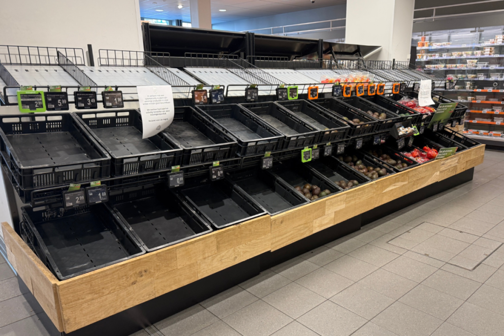 Leere Regale und leere schwarze Kisten in der Obst- und Gemüseabteilung eines Albert-Heijn-Supermarkts während einer IT-Störung.