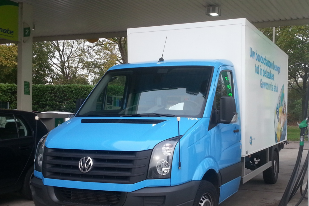 Ein blau-weißer Lieferwagen von Albert Heijn steht an einer Tankstelle.