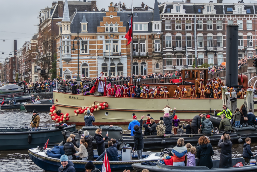 Das Dampfschiff „Spanje“, voll mit Nikolaus und seinen Helfern, fährt über die Amsterdamer Grachten, vorbei an belebten Kais und überfüllten Brücken mit begeistertem Publikum.