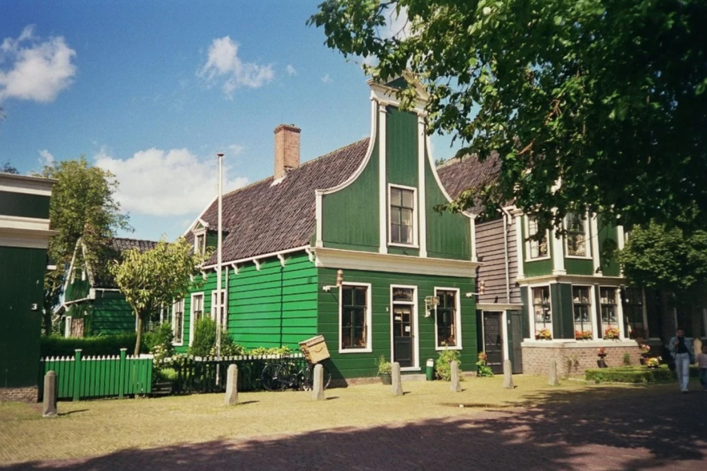 Grünes, holzverkleidetes Geschäftshaus im Zaandijker Stil des Albert-Heijn-Museumsladens auf der Zaanse Schans mit einem klassischen Fahrrad vor der Tür.