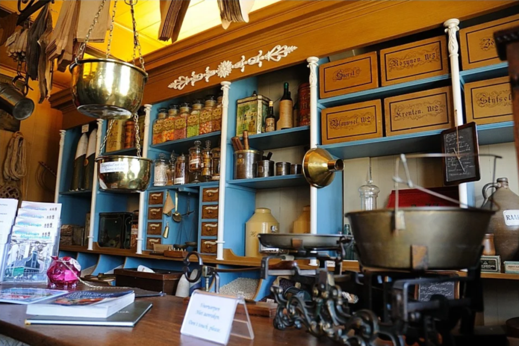 Nostalgisches Holzinterieur eines altmodischen Lebensmittelladens mit Messingwaagen, blauen Regalschränken und Blechvorratsdosen.