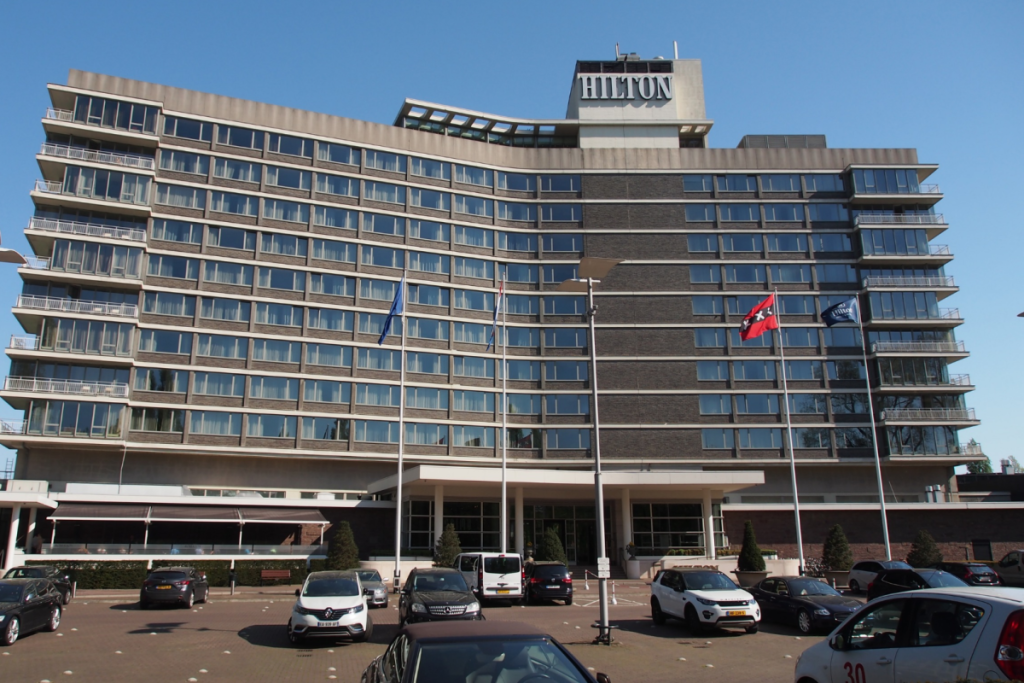 Fassade des Hilton-Hotels an der Apollolaan in Amsterdam-Süd mit Fahnen und Parkplatz.
