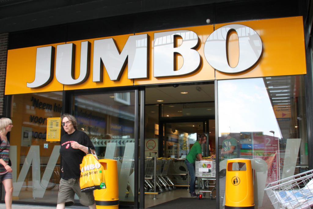Fassade und Eingang einer gelben Jumbo-Supermarktfiliale mit einkaufenden Passanten.
