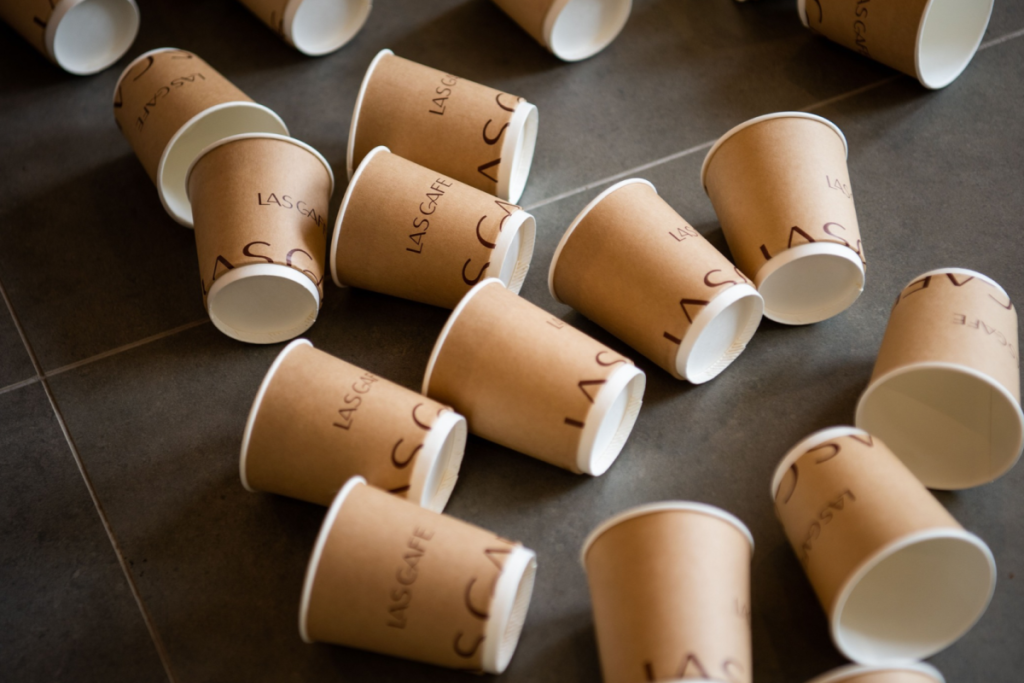 Diversi bicchieri da caffè monouso di cartone sparsi sul pavimento.