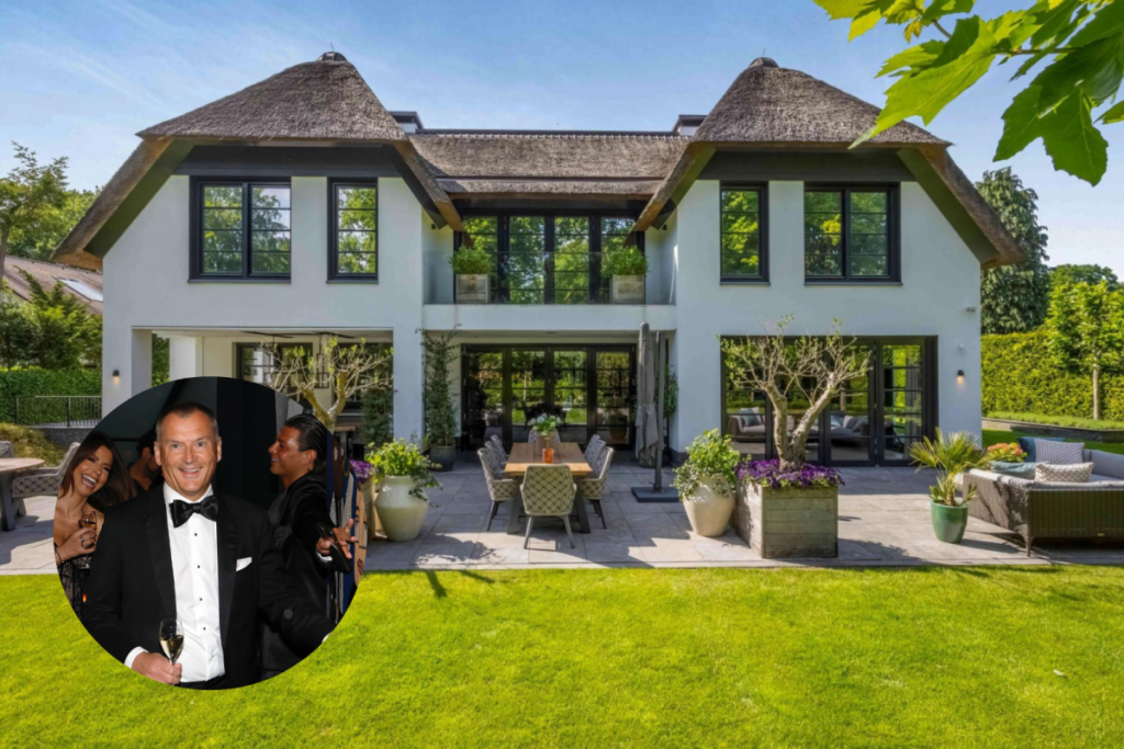 Achtergevel van de rietgedekte villa in Blaricum met een strak gemaaid gazon en terrasmeubilair op het zuiden.