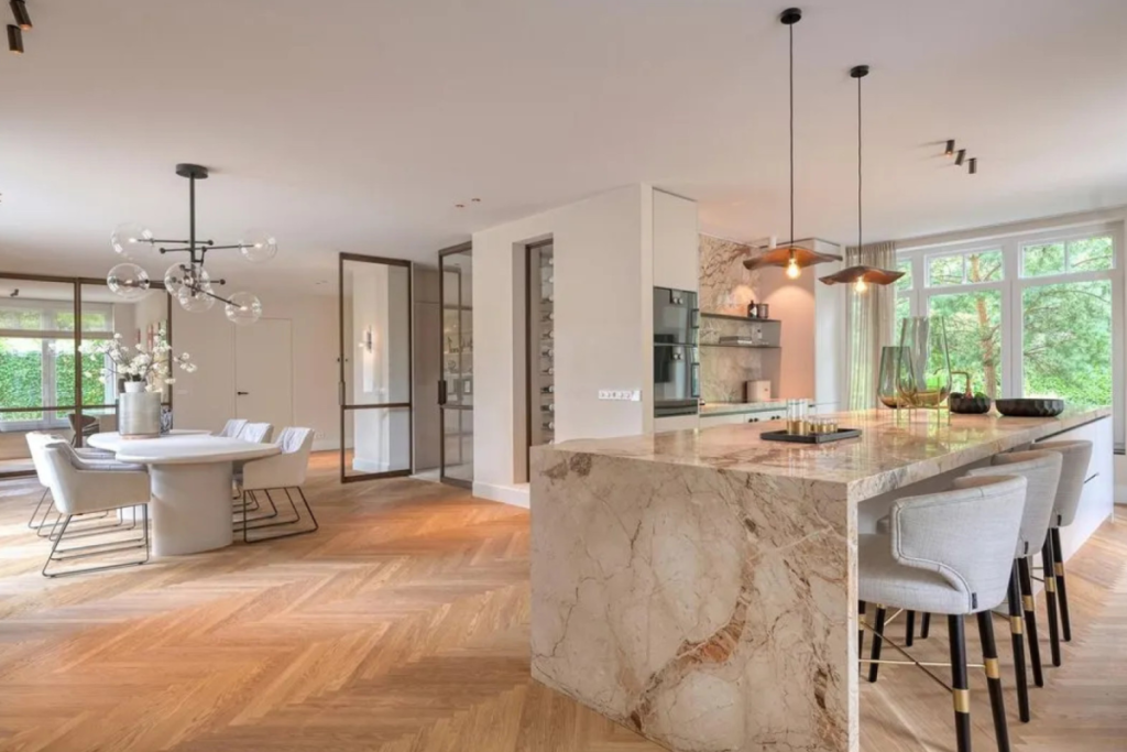 Luxe leefkeuken met een marmeren kookeiland en visgraatvloer in de verbouwde woning van Dirk Kuijt.