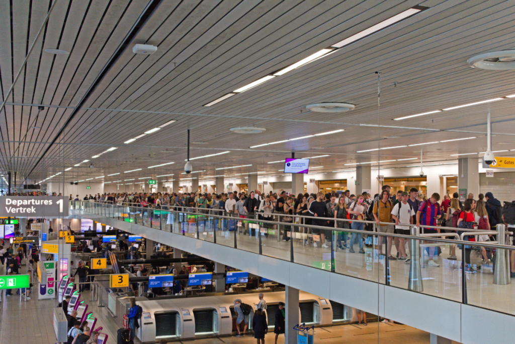 Drukke vertrekhal op Schiphol met lange wachtrijen voor de beveiligingscontrole bij Vertrek 1.