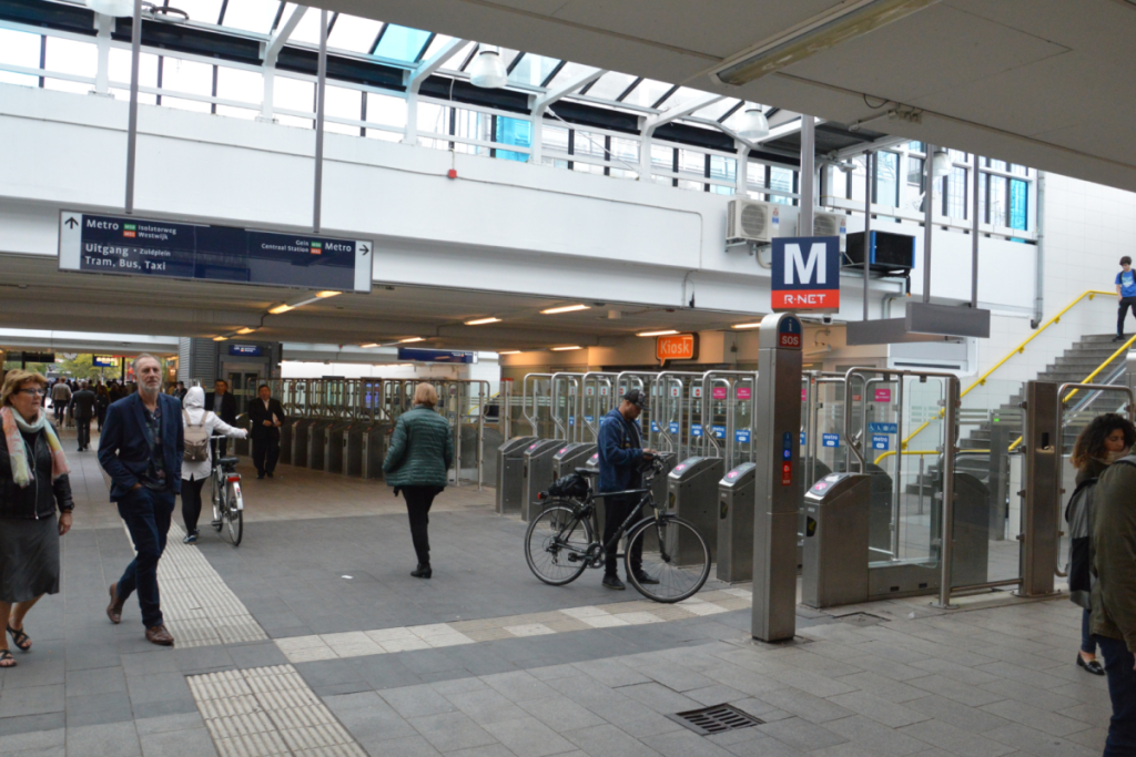 Reizigers passeren de tourniquets en incheckpoortjes in de Minervapassage van Station Amsterdam Zuid.