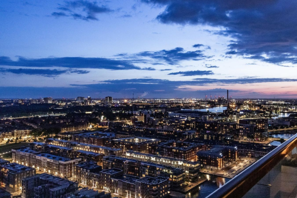 Panoramisch uitzicht in de avond over de Amsterdamse Houthavens vanaf het balkon van het Pontsteiger-penthouse.