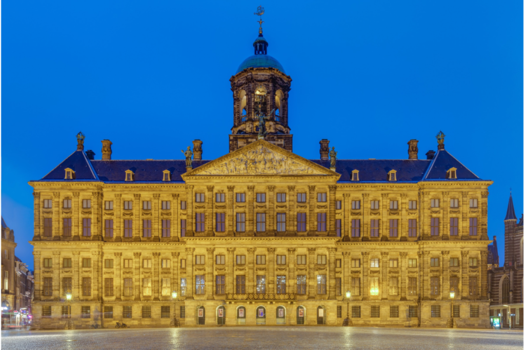 Verlichte voorgevel van het Koninklijk Paleis Amsterdam op de Dam tijdens de schemering