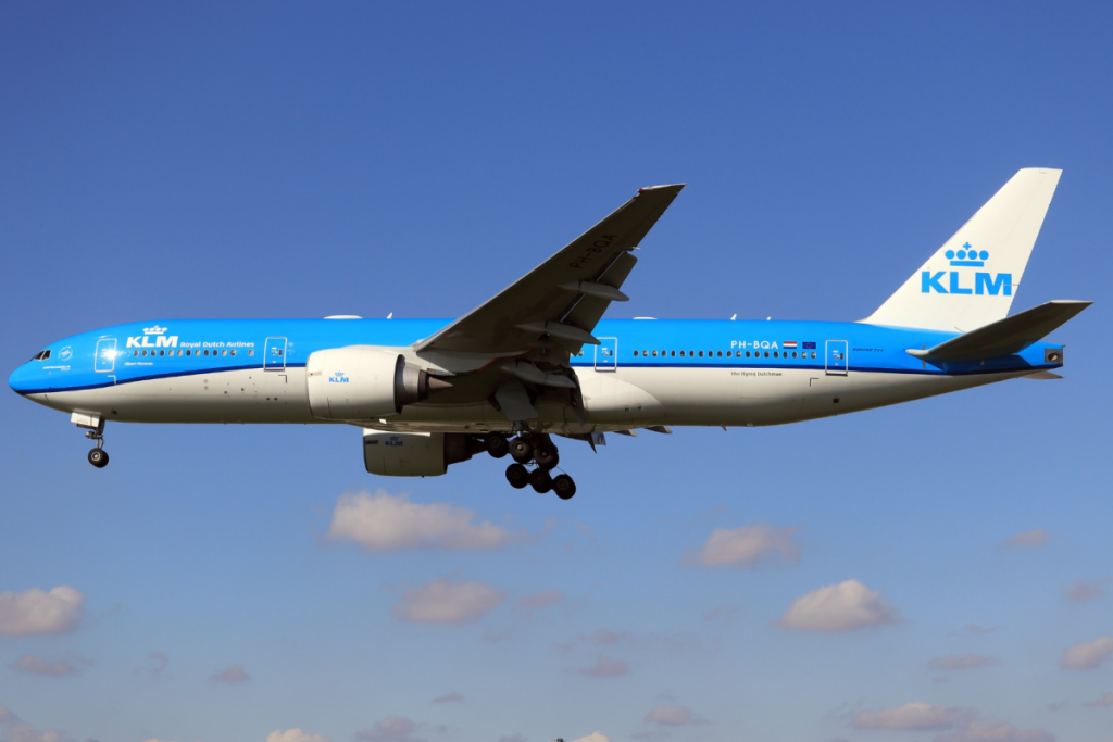 Blauw-wit KLM-passagiersvliegtuig tijdens de landing tegen een helderblauwe lucht