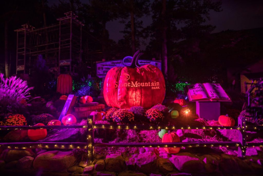 una enorme calabaza luminosa rodeada de decoraciones de Halloween