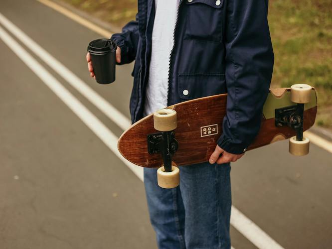 someone holding a coffee and a skateboard