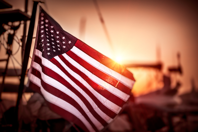Flag of United States of America flutters in the winds in mild sunset light. Holiday Celebration of an independence day of USA. 4th of July.