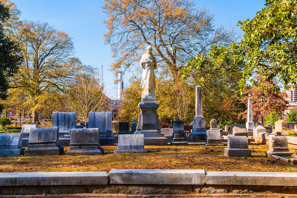 Group of tombstones and sculpture of Virgin Mary on the Oakland Cemetery in sunny autumn day, Atlanta, USA
