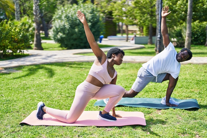 African american man and woman couple doing yoga exercise at park
