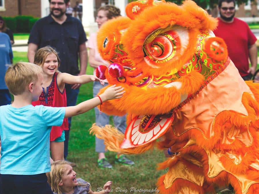 children pet an orange dragon puppet at a lunar new year festival