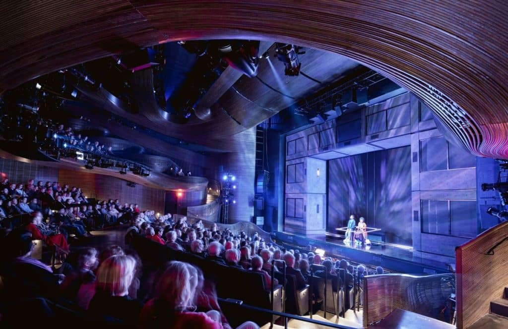 Interior del Alliance Theatre de Atlanta, donde se está celebrando una representación; la iluminación es de color morado y azul, y la imagen muestra el escenario desde el público.