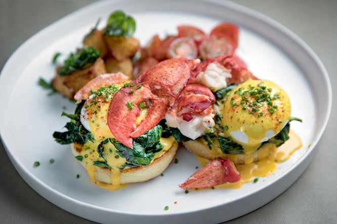 Eggs Benedict with lobster served on a round plate with sauteed potatoes