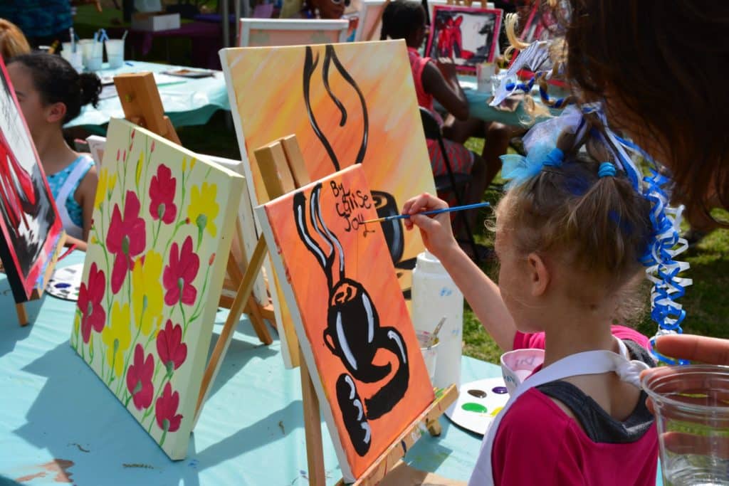 little girl painting at a festival