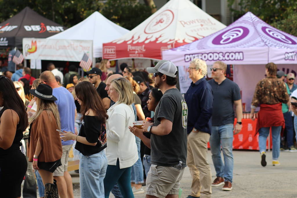 carpas instaladas en un festival de salsa picante y gente haciendo cola para probarla