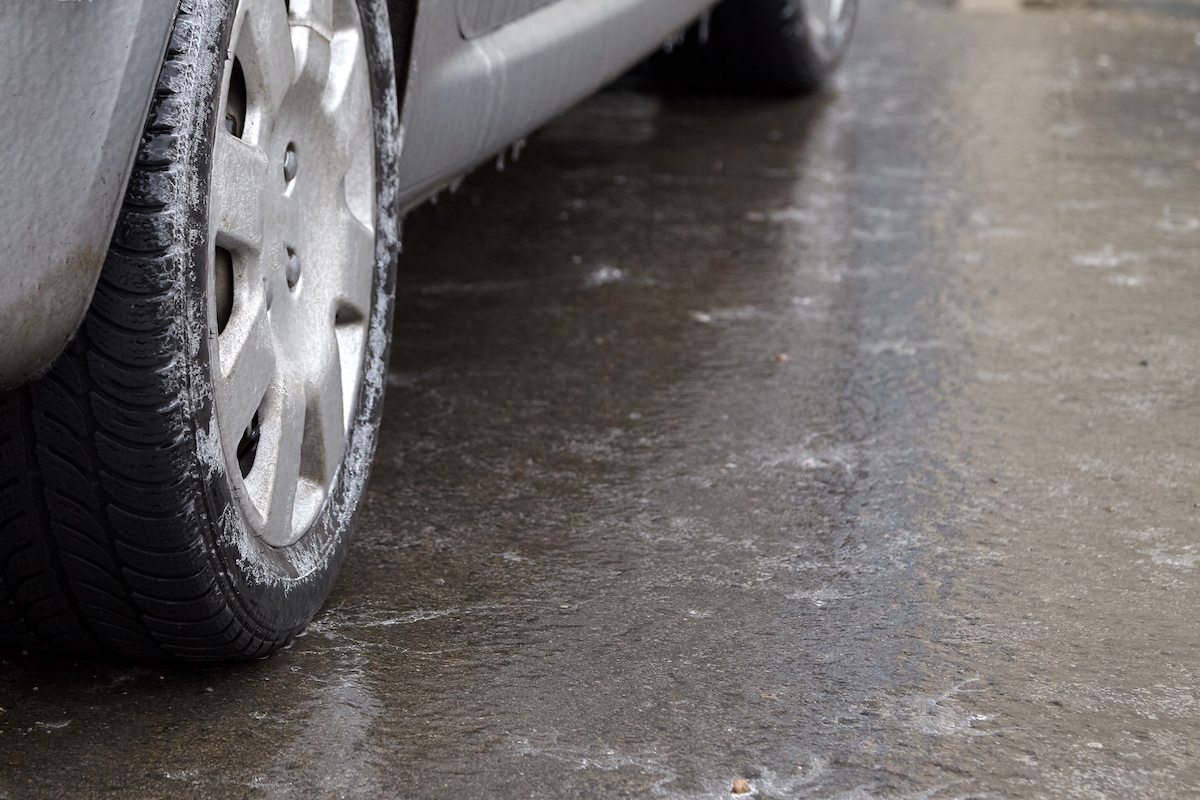 Ice crusted ground, car wheel on icy road, hazardous weather conditions, winter street