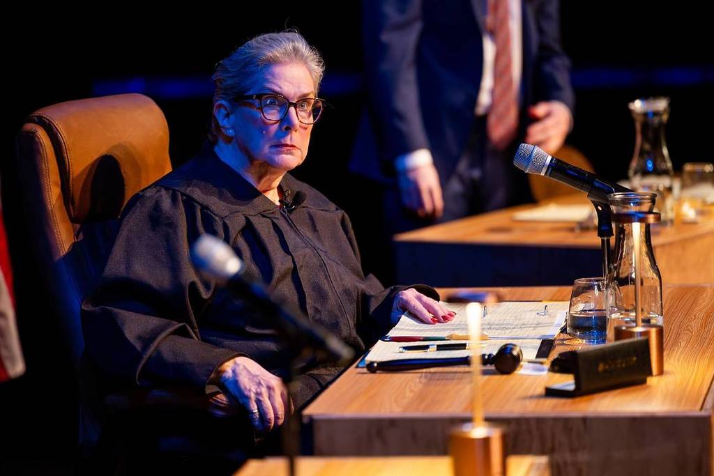 The judge sits behind the bench at The Jury Experience.