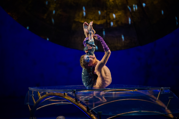 male contortionist forms his body into an impossible keyhole shape
