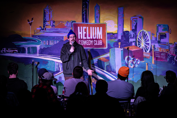 male comedian standing on a stage with a mic