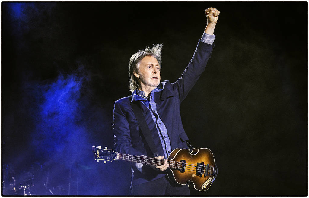 Paul McCartney holding a guitar on stage