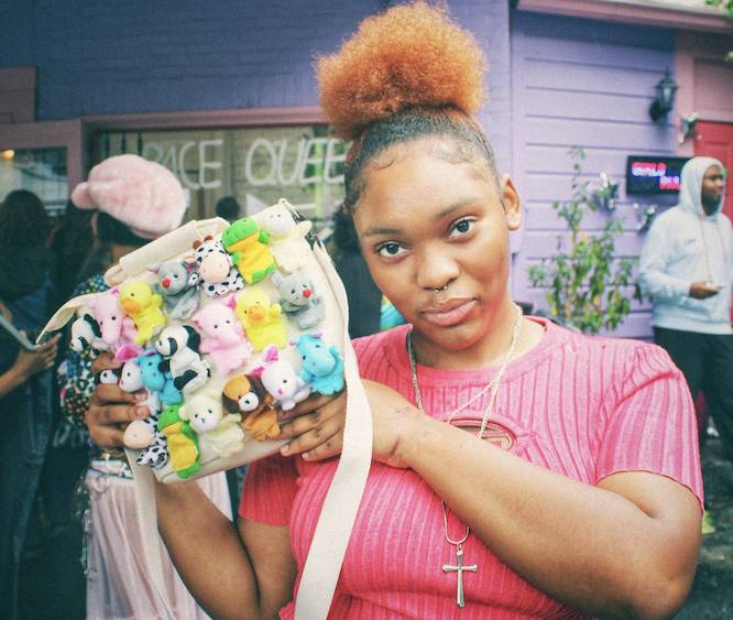 girl holding up a purse with little plushies on it